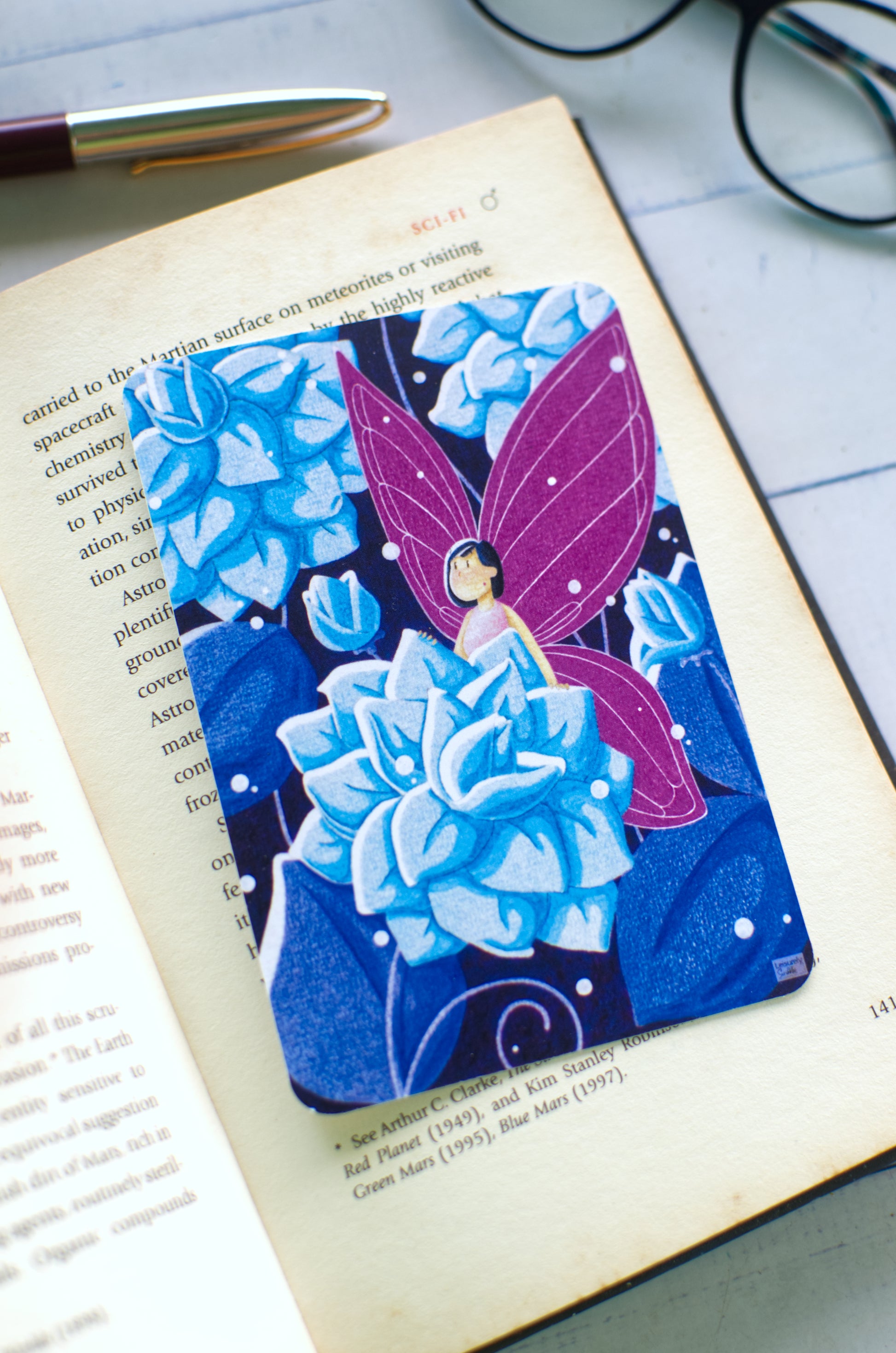 Whimsical hand-drawn fairy bookmark with pink wings and blue flowers